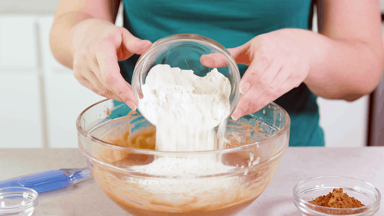 Flour being poured into a bowl of brownie batter