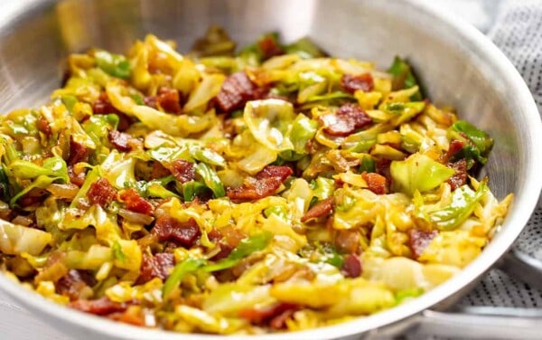Fried Cabbage and bacon mixed together in a stainless steel bowl.