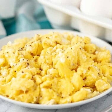 Lightly Peppered fluffy scrambled offs on a white plate.