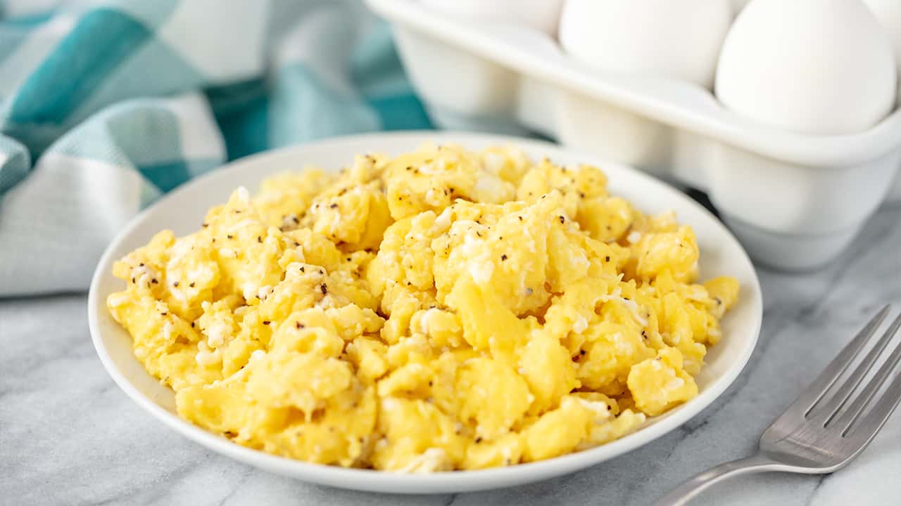 Lightly Peppered fluffy scrambled offs on a white plate.