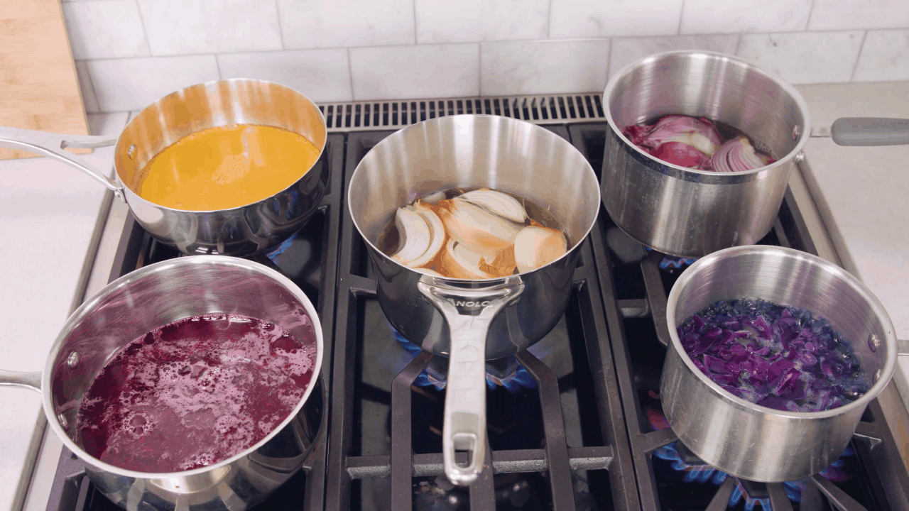 Five pots on the stove each with different ingredients in it.