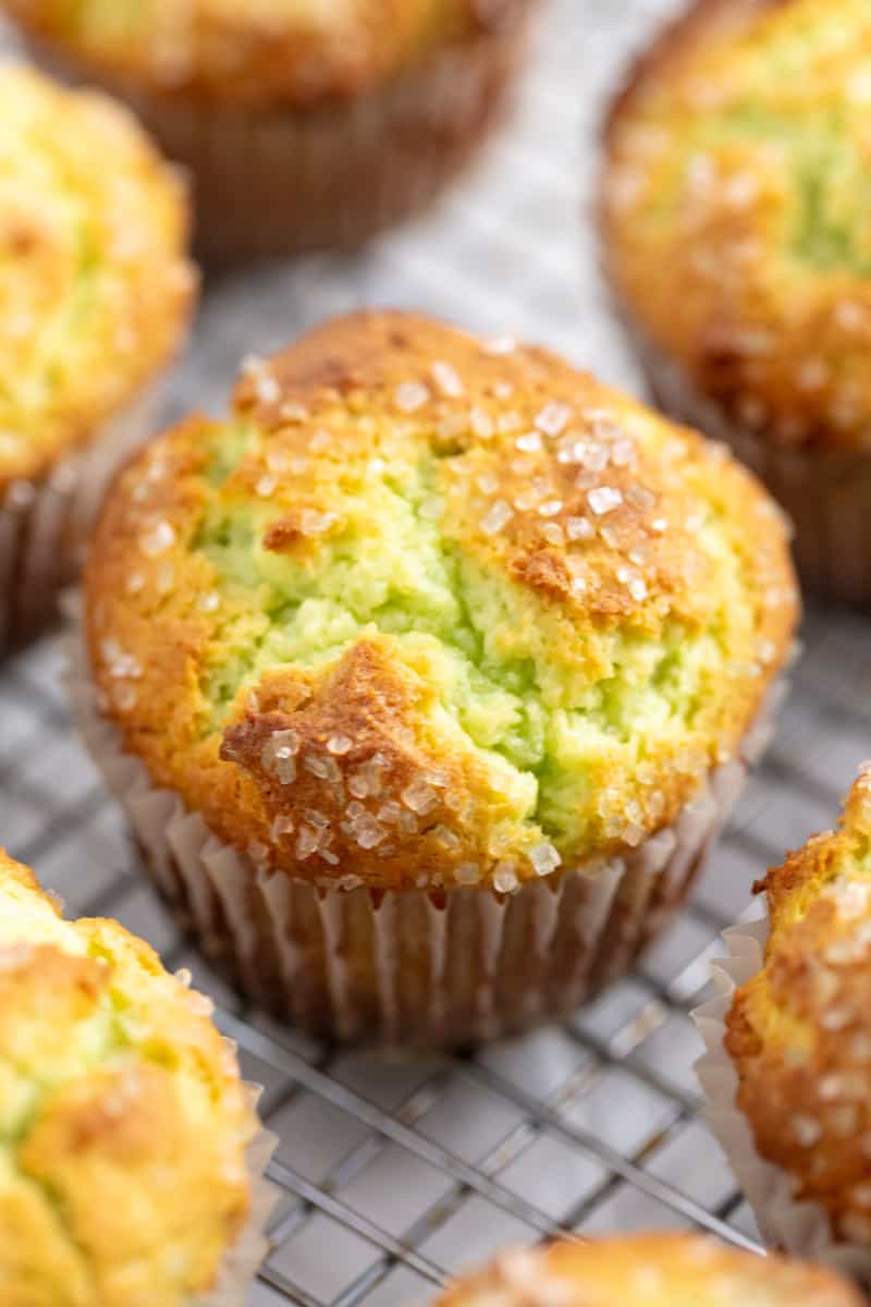 Angled photo of Pistachio Muffins on a wire rack.