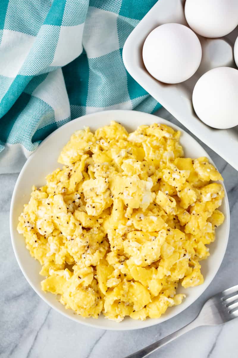 Bird's eye view of scrambled eggs on a white plate.