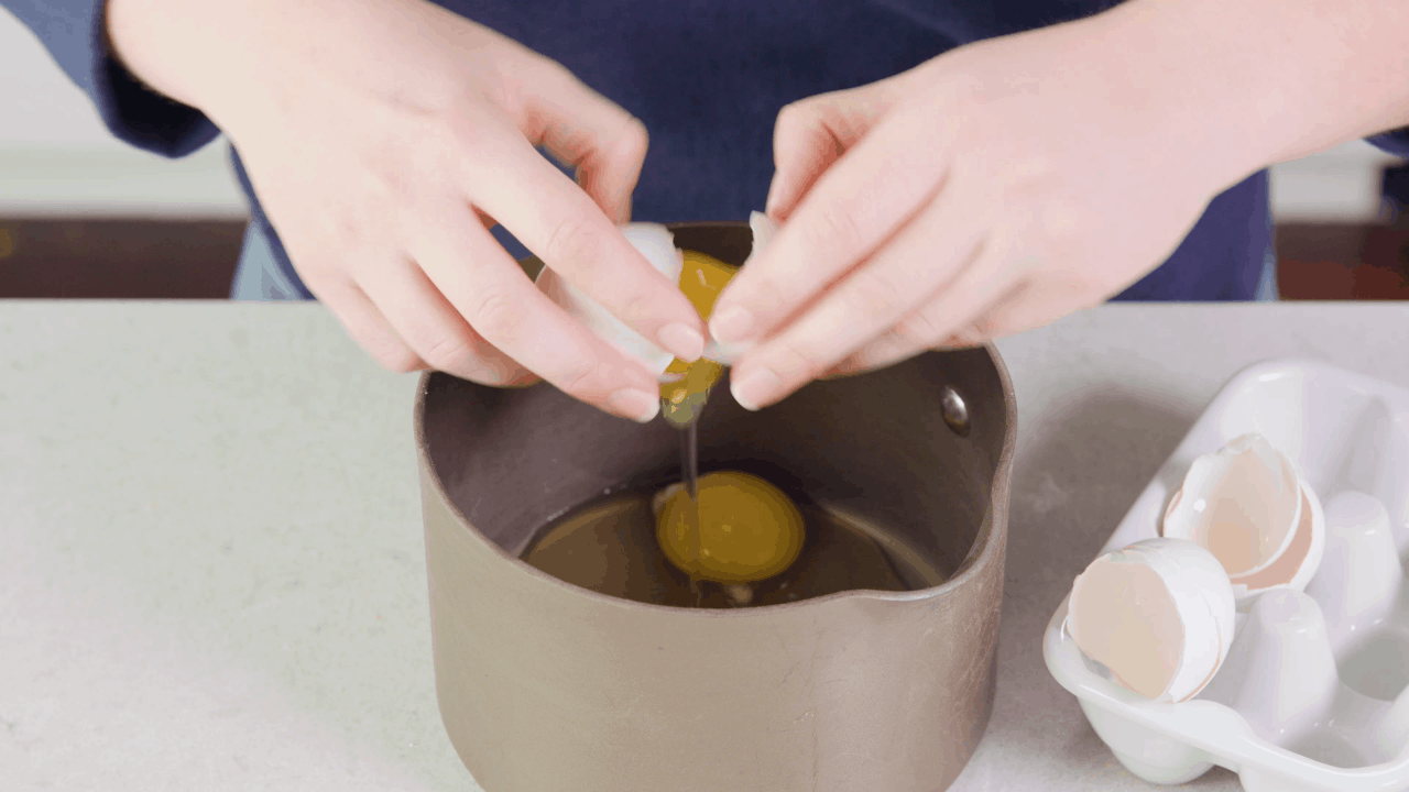 Eggs being cracked into a cold saucepan.