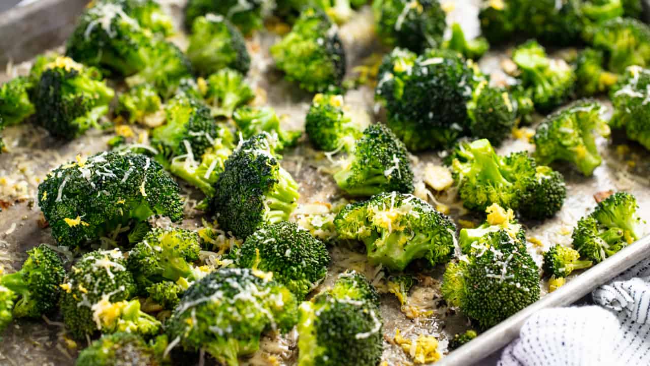 Roasted Broccoli sprinkled with melted cheese on a baking sheet.