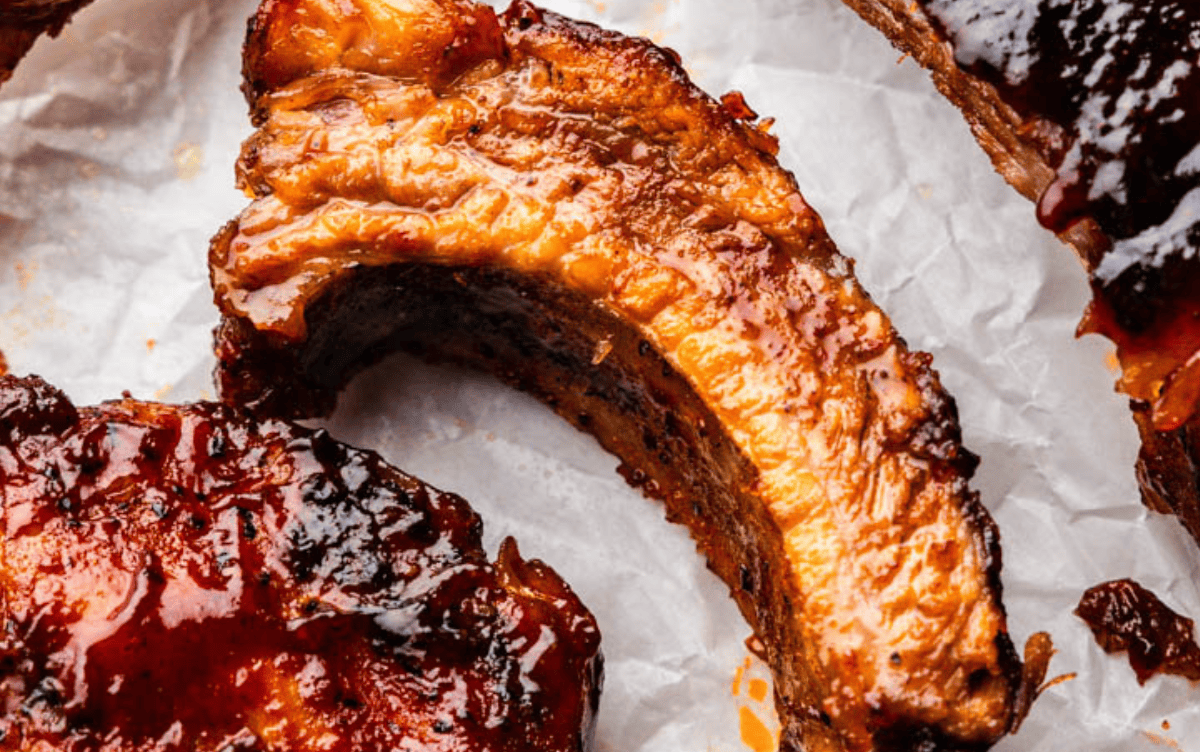 A close up view of individual slow cooker pork ribs on parchment paper.