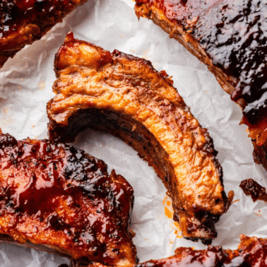 A close up view of individual slow cooker pork ribs on parchment paper.