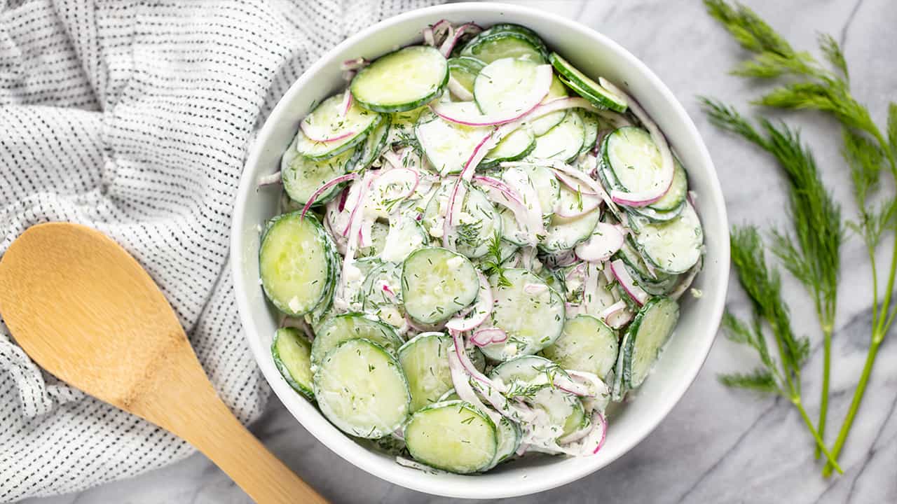 Bird's eye view of creamy cucumber salad filled in a white bowl.