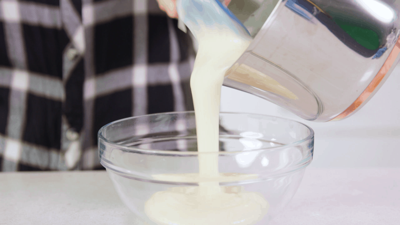 Ermine Frosting being poured into a glass bowl.