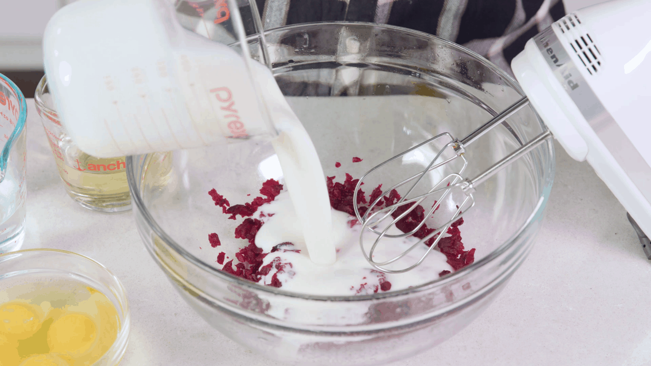 Milk being poured into a bowl of beets. 