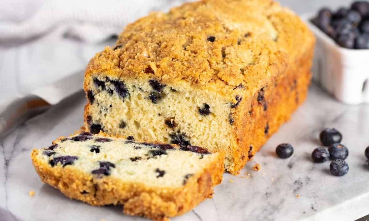 Loaf of Blueberry Pancake Bread on a marble slab with the end sliced to reveal a cross-section of blueberries inside.
