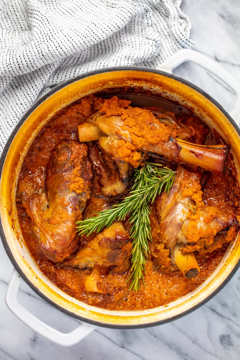 Bird's eye view of Braised Lamb Shanks in a ceramic cooking pot.