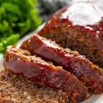 Meatloaf sliced and on a white plate.