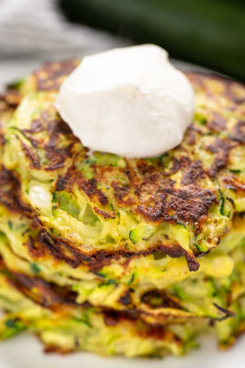 Close up of Zucchini Pancakes topped with sour cream.