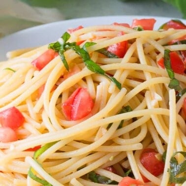 Tomato Pasta in a white bowl topped with basil.