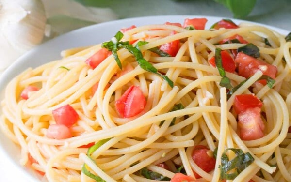 Tomato Pasta in a white bowl topped with basil.