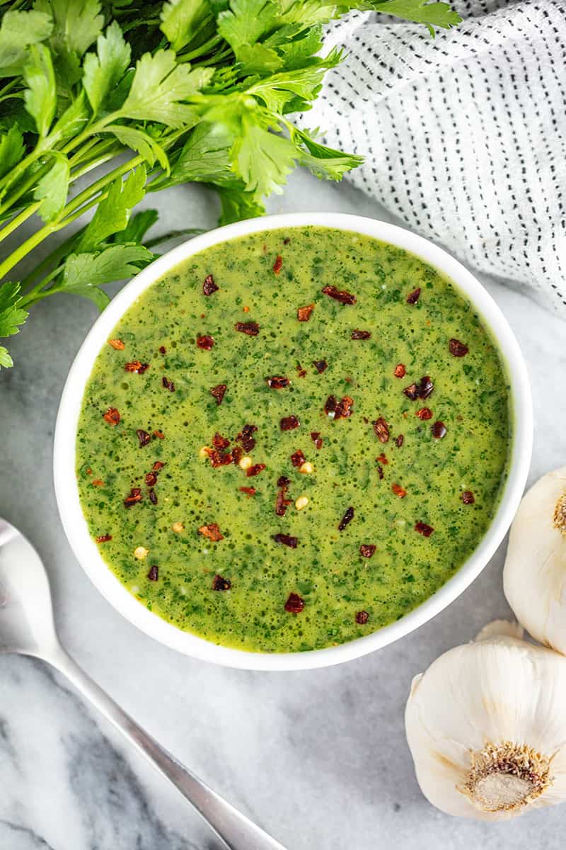 Bird's eye view of Chimichurri sauce in a white bowl.