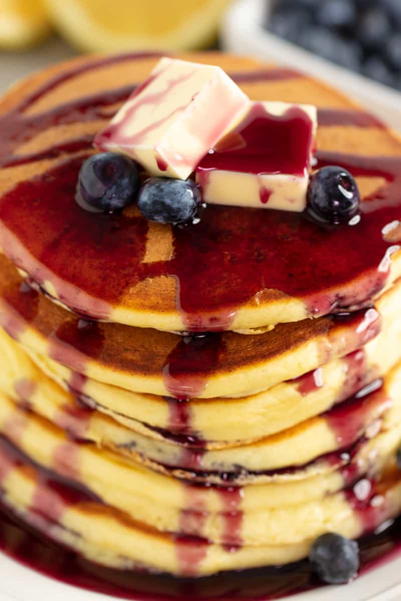 Bird's eye view of A stack Lemon Ricotta Pancakes covered with syrup and topped with berries and butter.