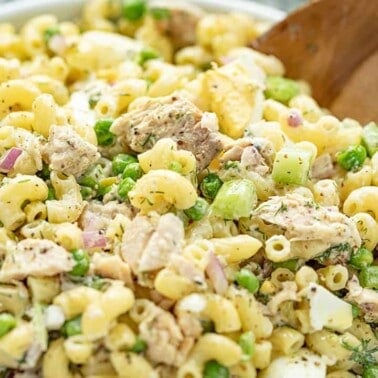 Tuna Macaroni Salad served from a white bowl with a wooden spoon.