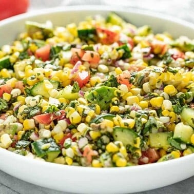 Fresh Corn Salad in a white bowl setting on a marble countertop.