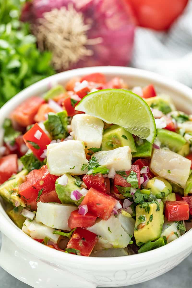 Ceviche topped with a lime wedge in a white bowl.