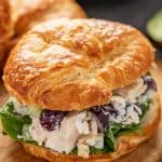 Close up of Chicken Salad in a croissant sandwich sitting on a cutting board.