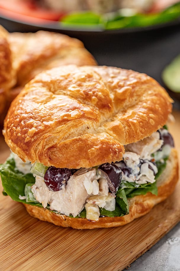 Close up of Chicken Salad in a croissant sandwich sitting on a cutting board.