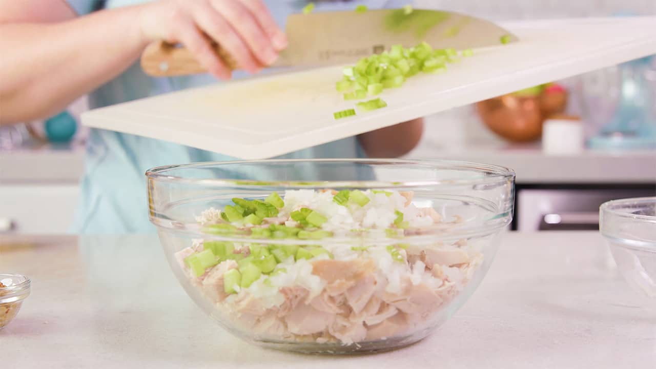 Add celery to ingredients in mixing bowl using Kitchen Knife to scrape celery into the bowl from off the cutting board.