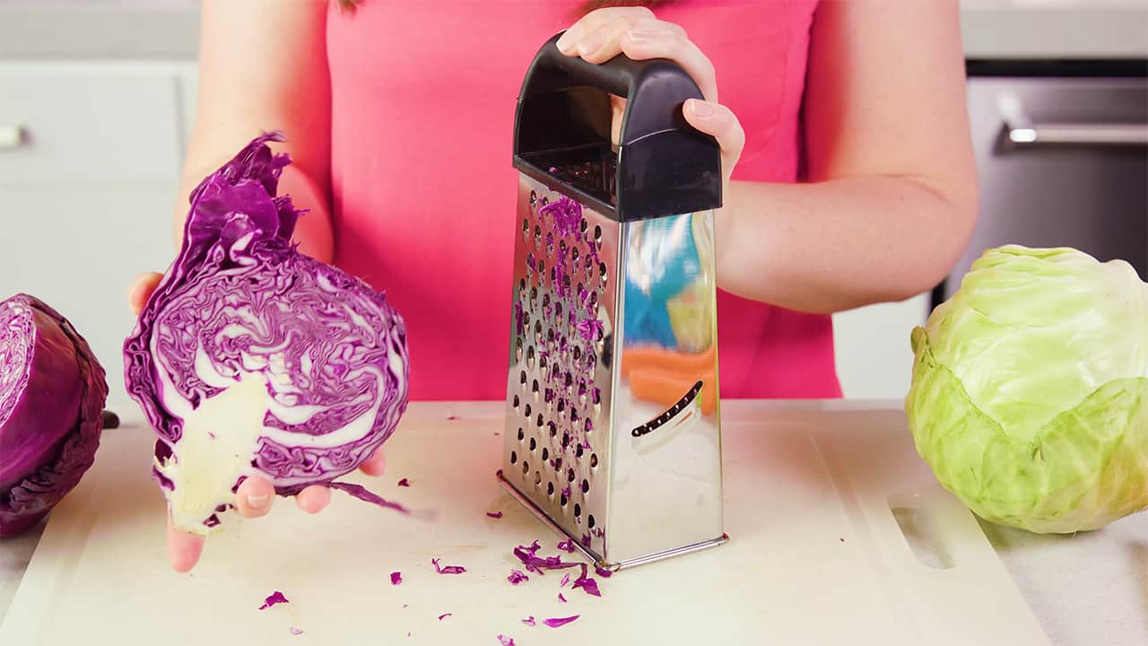 Using a cheese grater on a cutting board, slice red cabbage to desired amount.