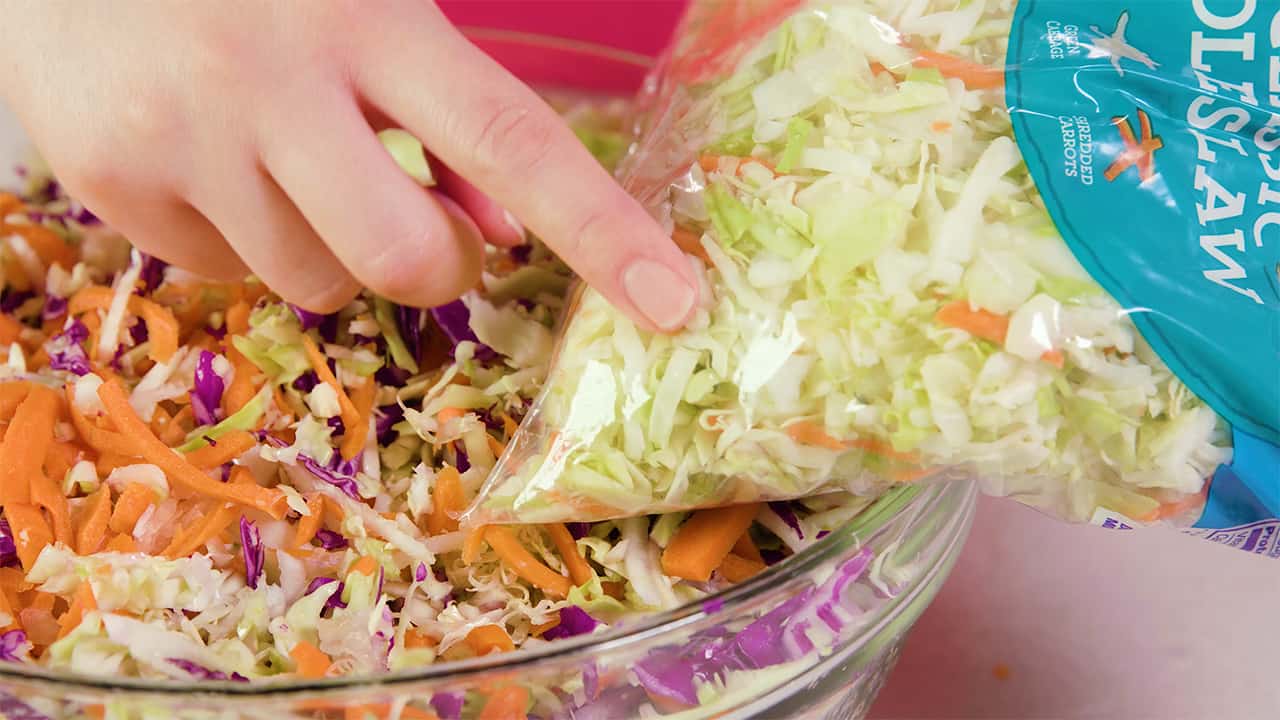 Side by side comparison of the filled mixing bowl ingredients of red and green cabbage, carrots and onion versus the pre-bagged coleslaw you can buy in the store. Homemade is much better!