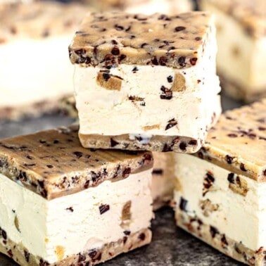 Three Cookie Dough Ice Cream Sandwiches stacked on a metallic surface.