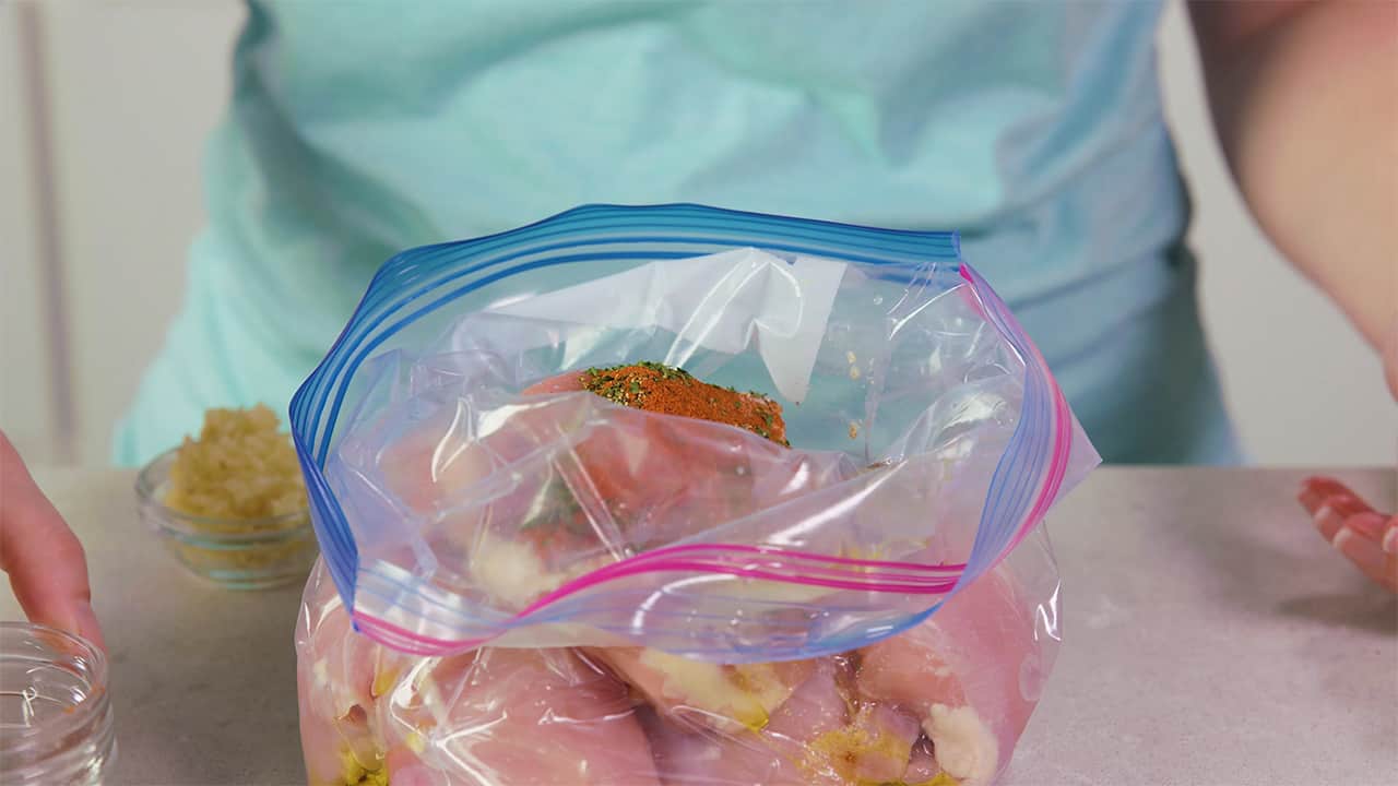 Add herbs and spices to gallon sized clear plastic bag filled with chicken breasts to add flavor to the marinade.