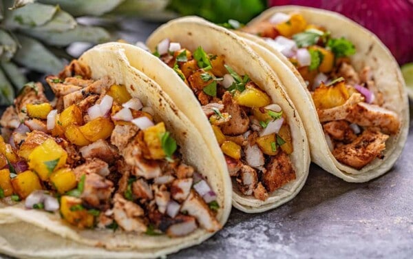 Angled view of Tacos Al Pastor on a black countertop.