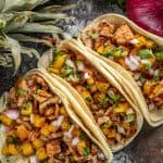 Bird's eye view of Tacos Al Pastor on a black countertop.