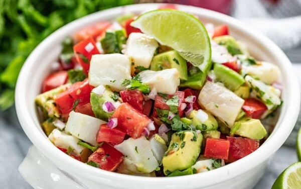 Ceviche topped with a lime wedge in a white bowl.
