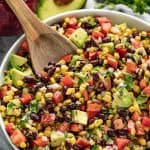 Black Bean and Corn Salad in a white bowl with a wooden spoon in it.