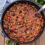 Bird's eye view of Chili in a Cast Iron Dutch Oven with a metal ladle in it.