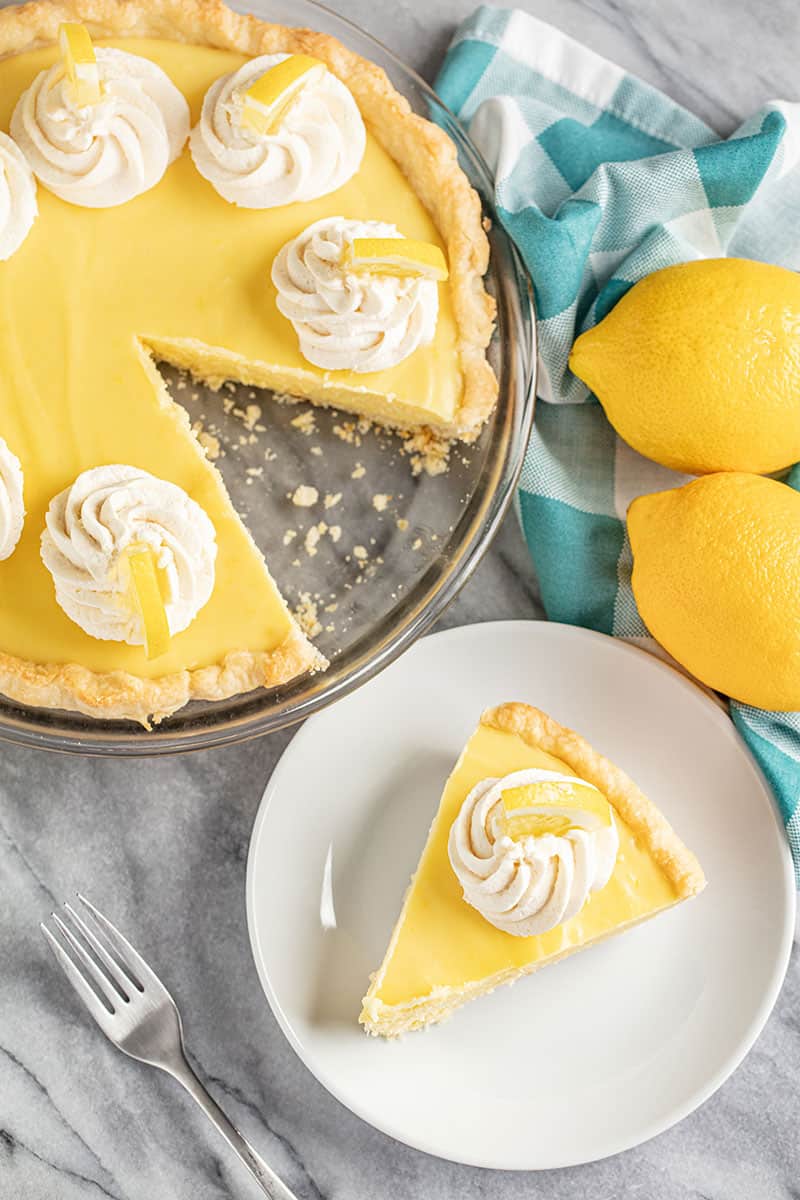 Old Fashioned Creamy Lemon Pie topped with dollops of stabilized whipped cream and lemon wedges 