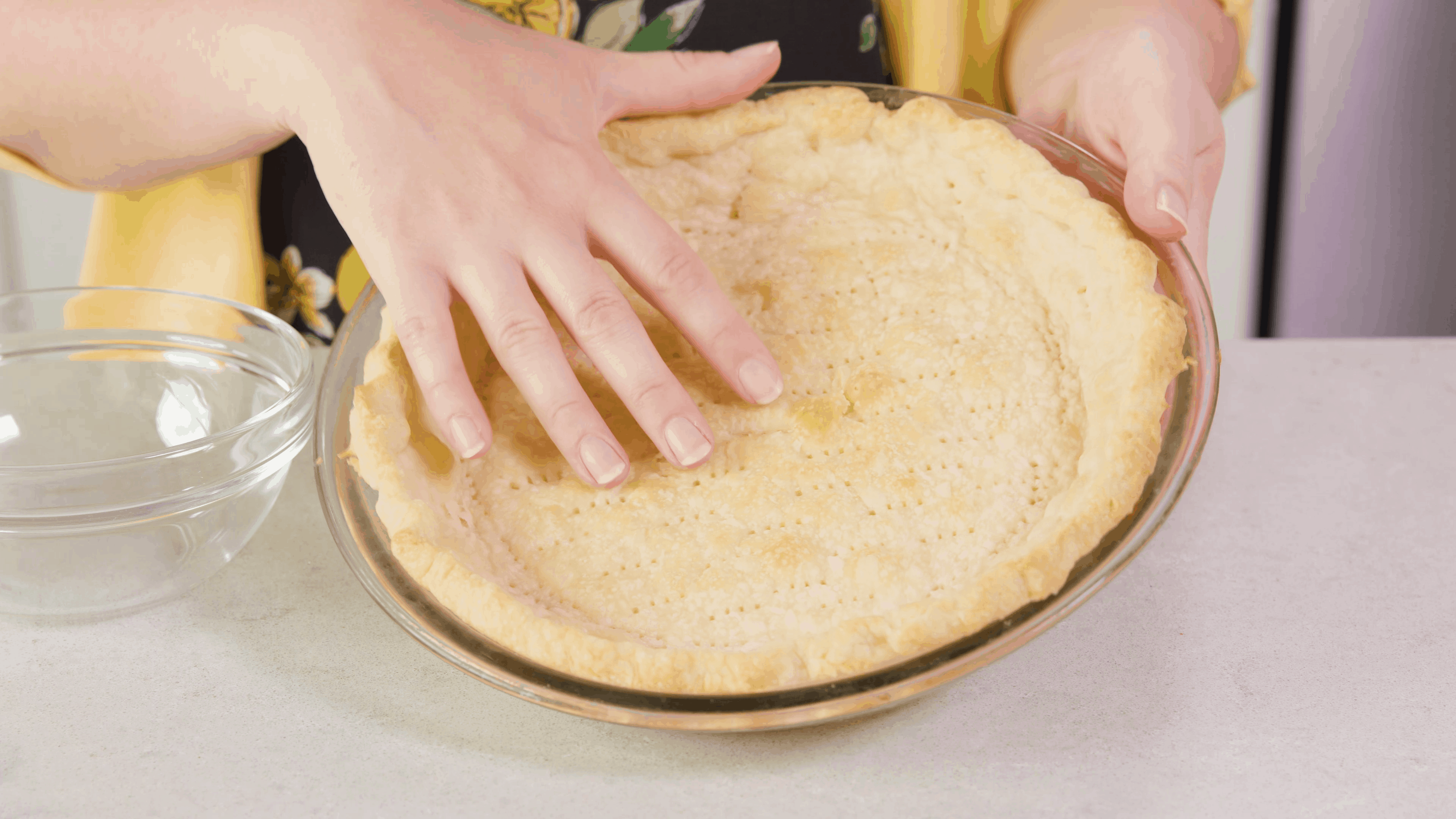 Angled view of pre-prepared pie crust in pie plate tilted on countertop.