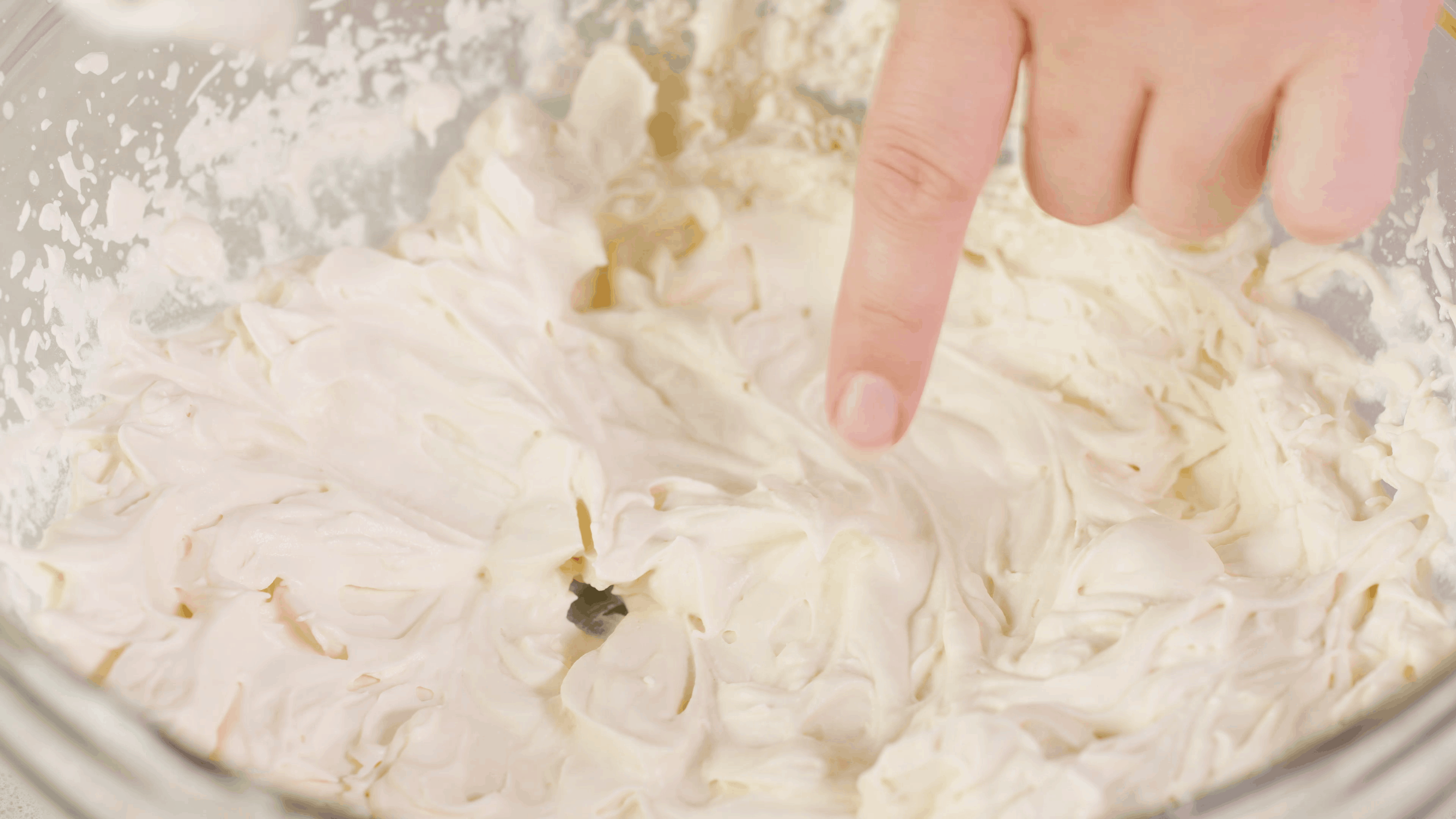 Close-up view of stabilized whipped cream in a clear mixing bowl.