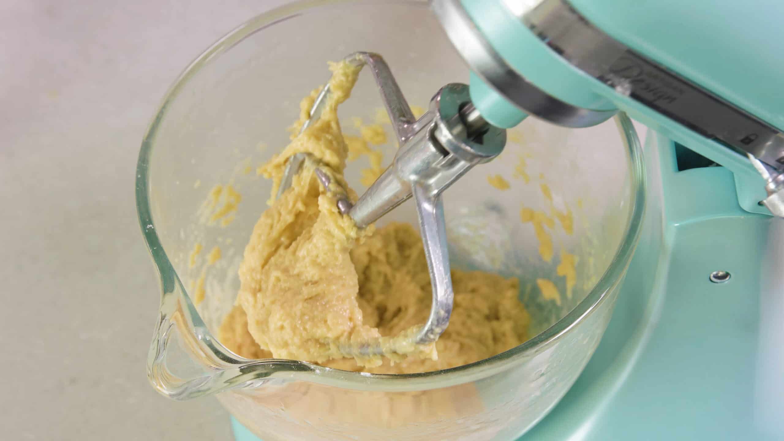 Close-up view of mixing bowl with the mixing attachment to the mixer showing the texture of the batter.