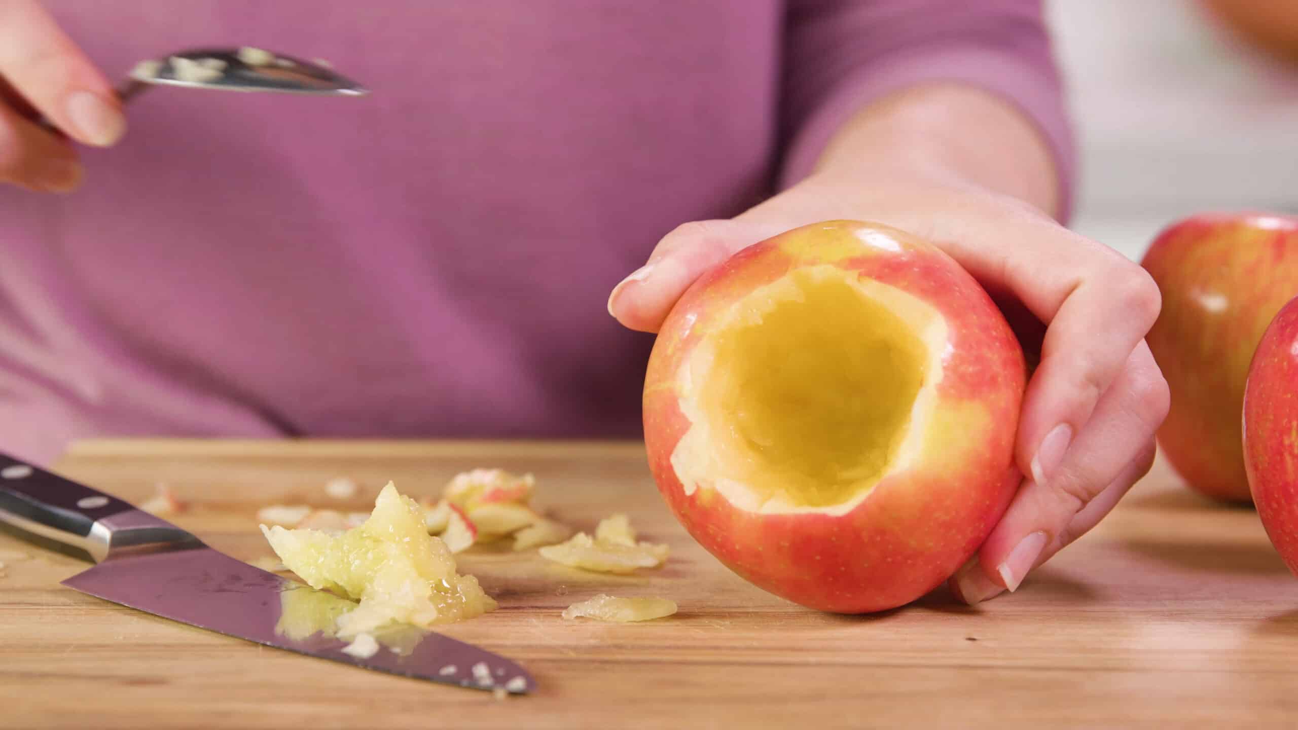 An apple on a cutting board viewed from the top in to see the core is removed creating a bowl shape.