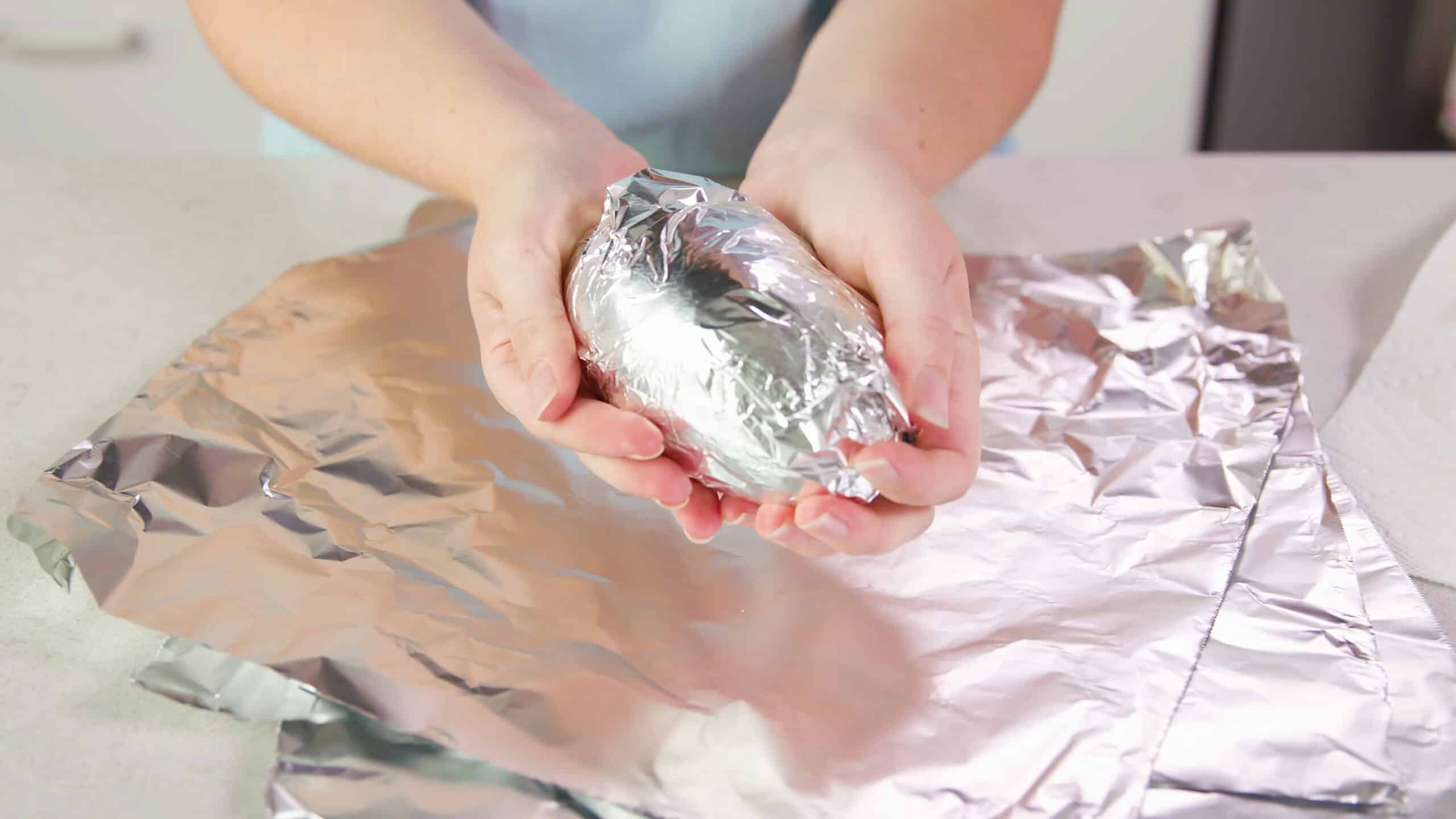 Roll each of the sweet potatoes into aluminum foil squares.