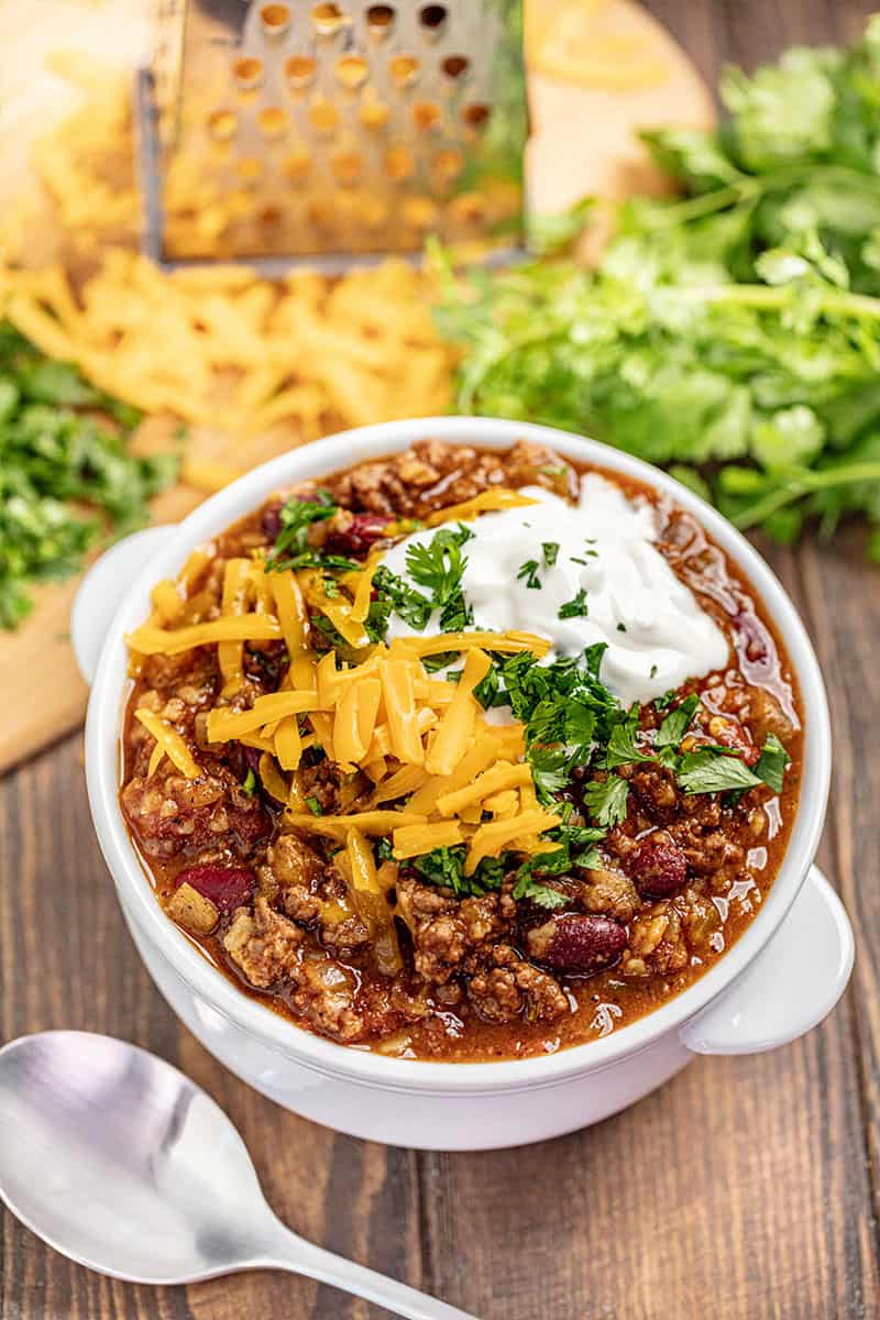 Bird's eye view of Chili topped with parsley cheese and sour cream in a white bowl.