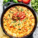 Queso Fundido in a skillet with bubbly cheese and topped with chorizo, fresh chopped tomato and cilantro