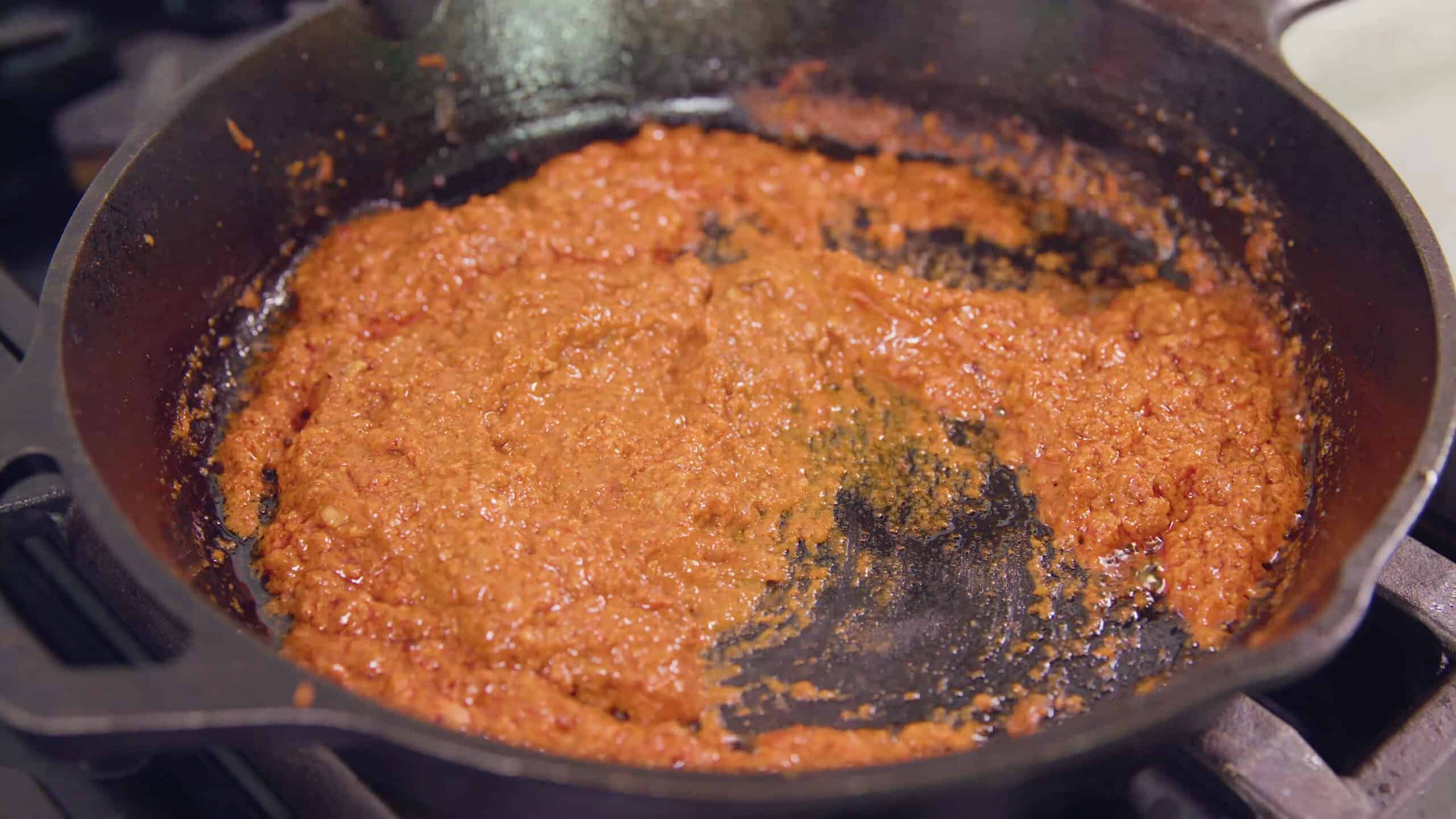 Close-up view of cast iron skillet on a stovetop with sizzling chorizo.