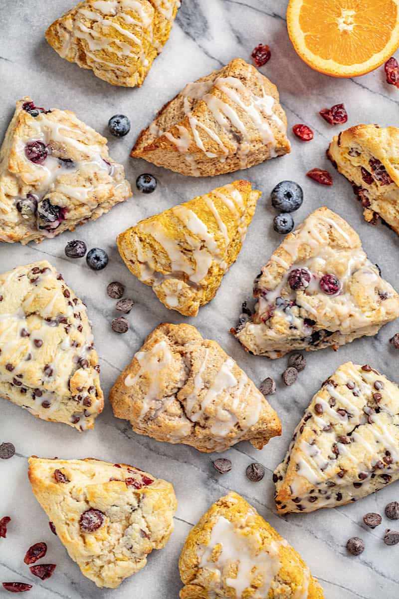 Bird's eye view of British Scones in various flavors. Chocolate Chip scones, Pumpkin Scones, Cranberry Orange Scones, Blueberry Scones, and Cinnamon Scones