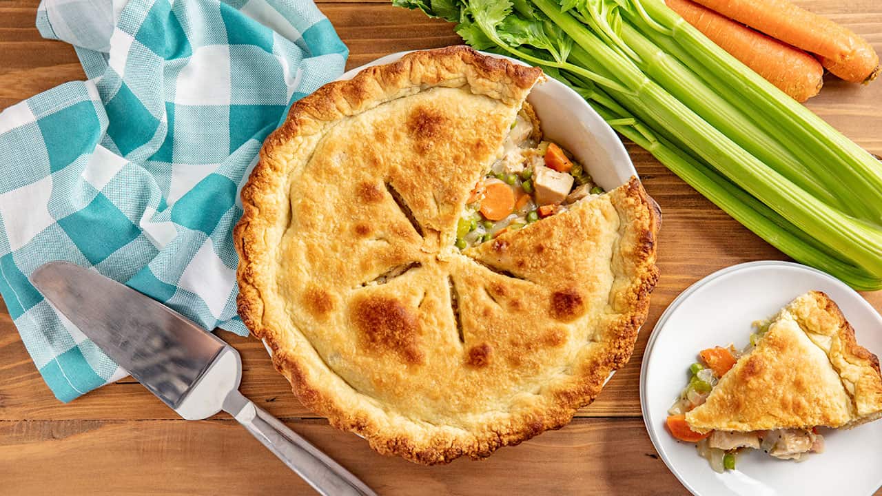 Bird's eye view of Chicken Pot Pie with a single slice cut out and placed on a white plate.