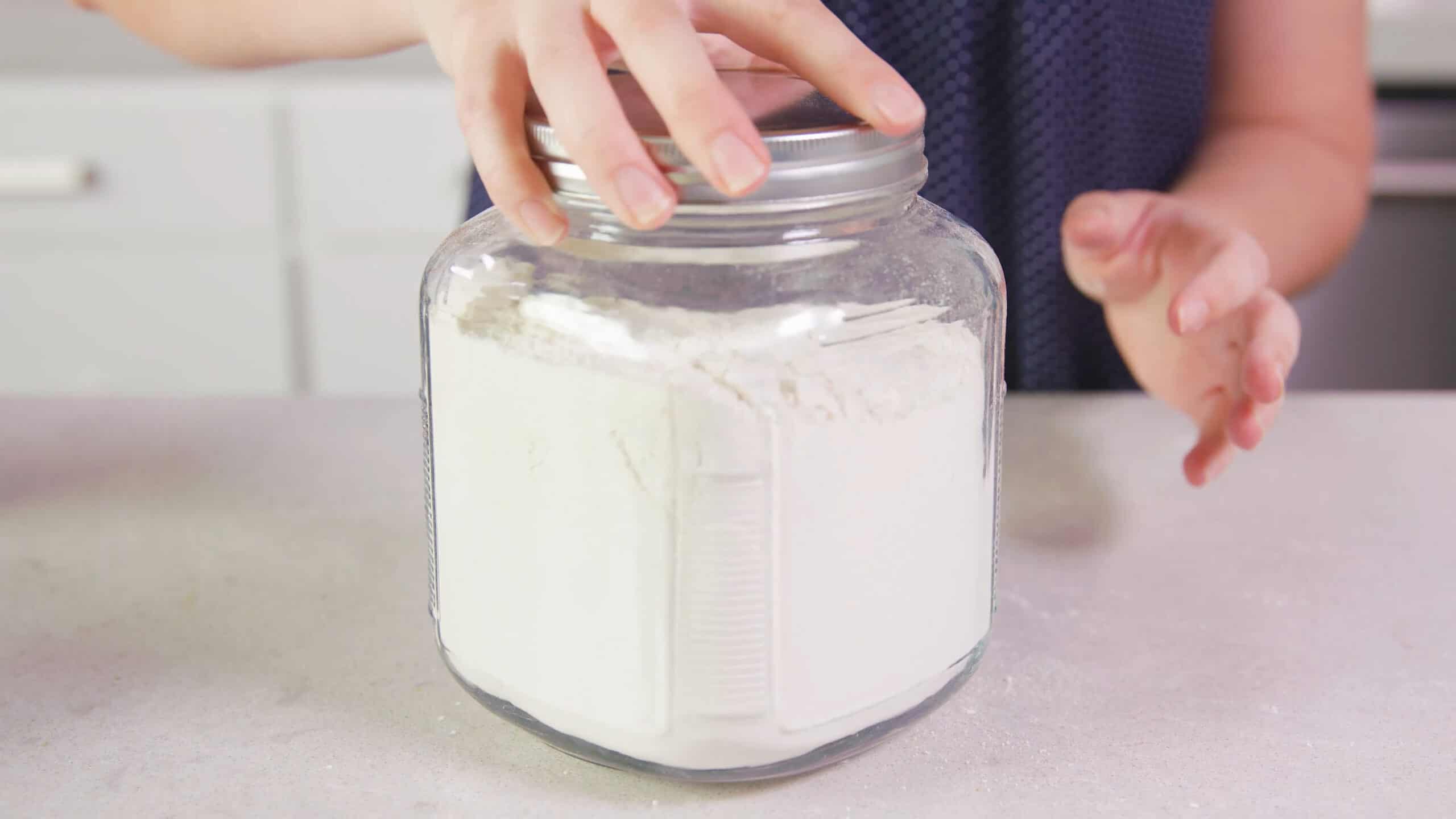 Close-up view of the full glass jar that holds the completed recipe of dry ingredients for the pancake mix and a silver lid twisted on top.