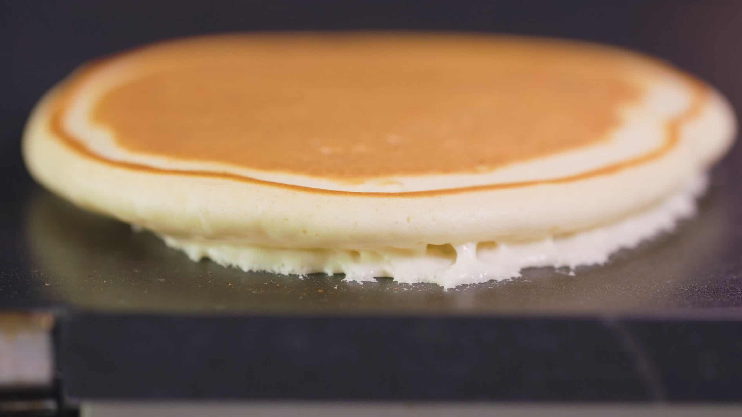 Close-up view of non-stick griddle with a golden brown pancake just flipped to show the perfectly brown side up.